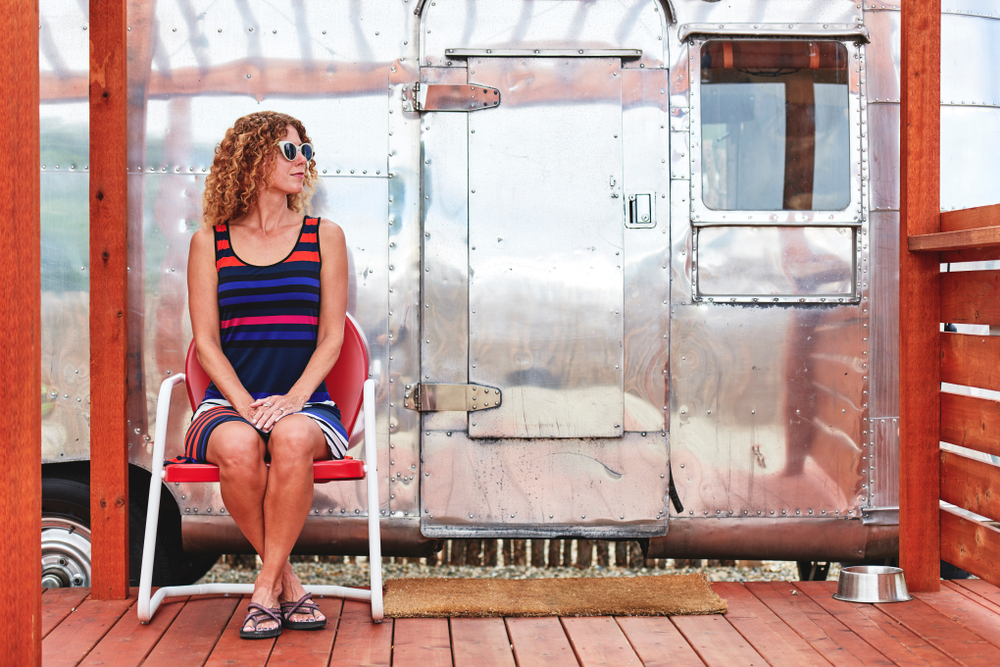 a young woman sitting next to a vintage camper