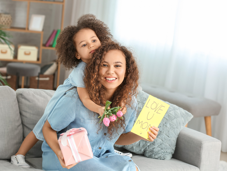 African-American woman with gift for Mother's Day received from her little daughter at home