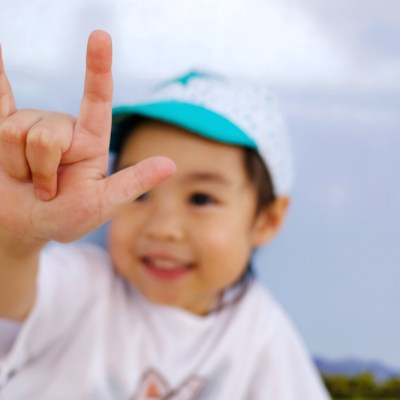 An adorable little asian girl show her hand, the sign hand language "I love you". Blured if her face, focus at her finger.