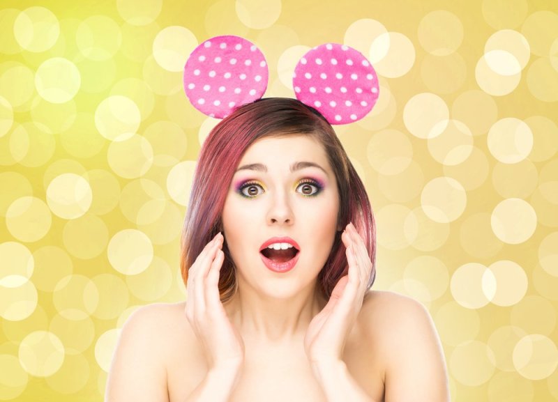 Beautiful young smiling woman in mickey mouse ears on bubble background.