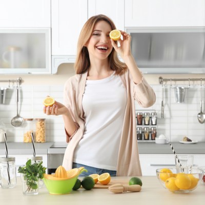 Beautiful young woman preparing lemonade in kitchen. Lemon-themed kitchen decor