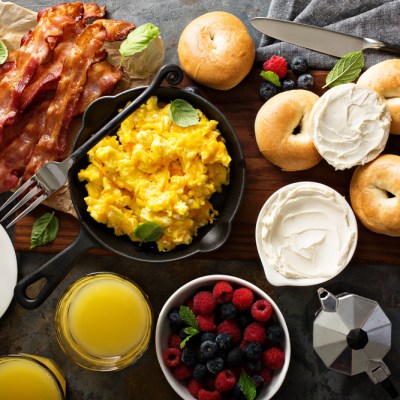 Big breakfast with bacon, bagels and scrambled eggs on the table overhead