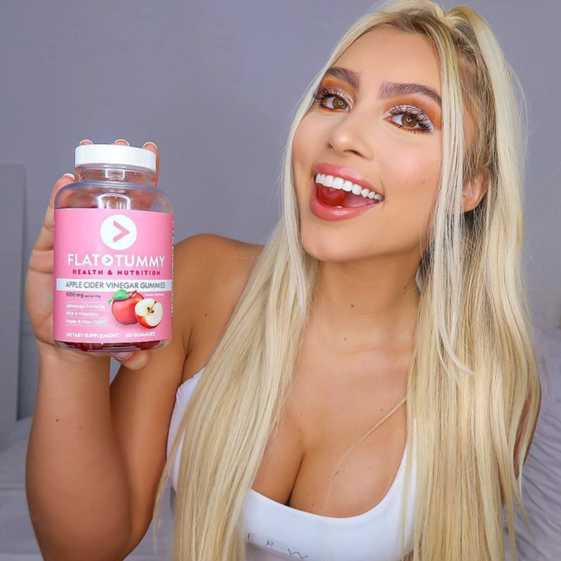 blonde woman taking a Flat Tummy apple cider gummy