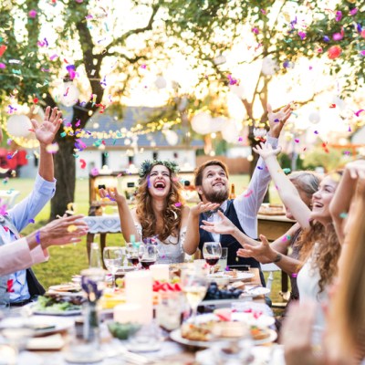 Bride and groom with guests at wedding reception outside in the backyard