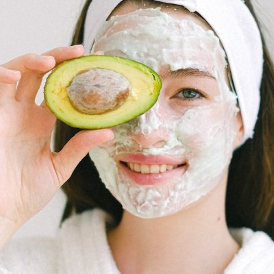 cheerful woman with face mask and avocado