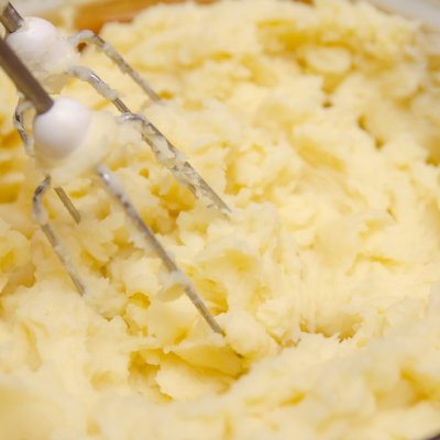 Close up woman's hand making mashed potato with mixer in saucepan. Cooking mashed potatoes.