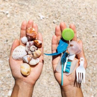 Concept of choice: save nature or continue to use disposable plastic. One hand holding beautiful shells, in the other - plastic waste. Beach sand on background. Environmental pollution problem.