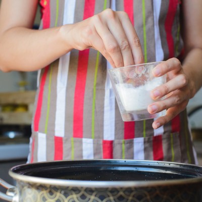 Cook takes cup of salt to water in bowl