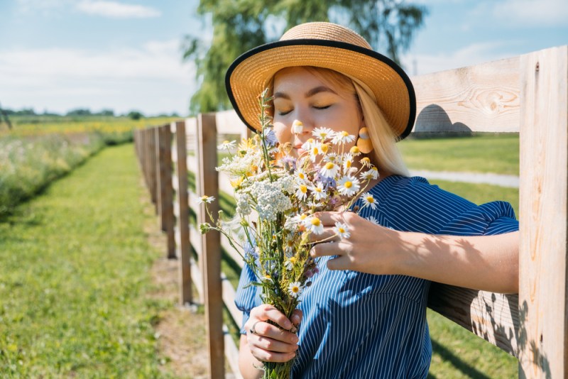 Cottagecore Farmcore Countrycore aesthetics, fresh air, countryside, slow life, pastoral life, outdoor picnics, wearing grandma clothes. Young girl in straw hat with flowers walks on country farm.