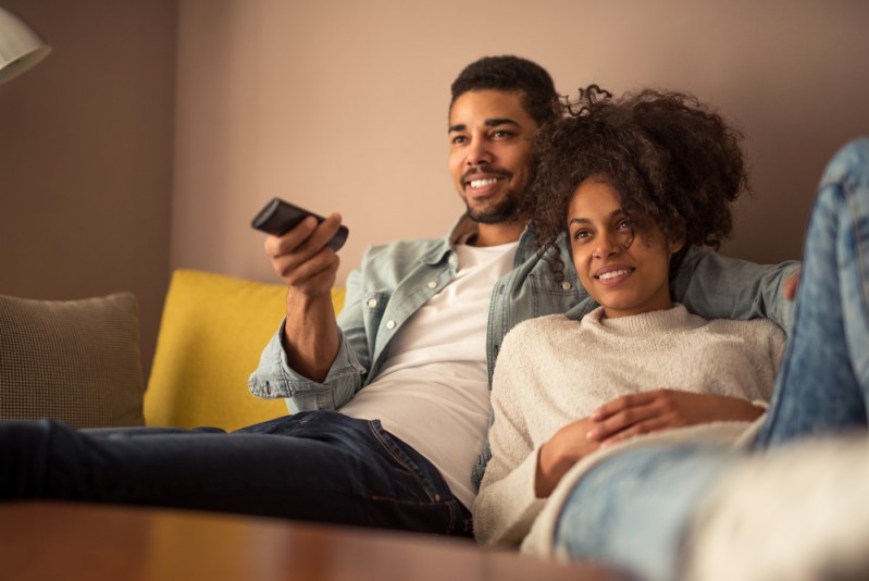 Cropped shot of a young Black couple watching television at home