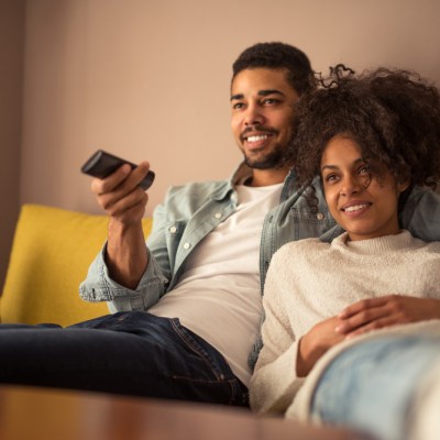 Cropped shot of a young Black couple watching television at home