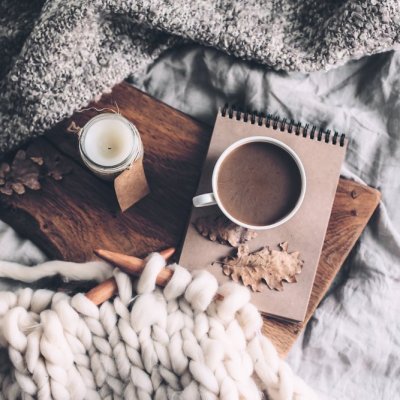 Cup of coffee and candle on rustic wooden serving tray in the cozy bed with blanket