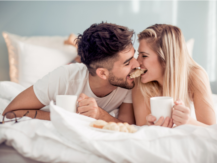 Cute couple having breakfast in bed in the bedroom.Couple lying in bed