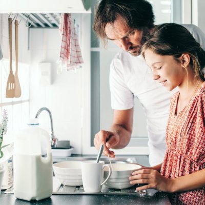 Dad with his 10 years old kid girl cooking in the kitchen, casual lifestyle photo series. Child making breakfast with parent together. Cozy homely scene.