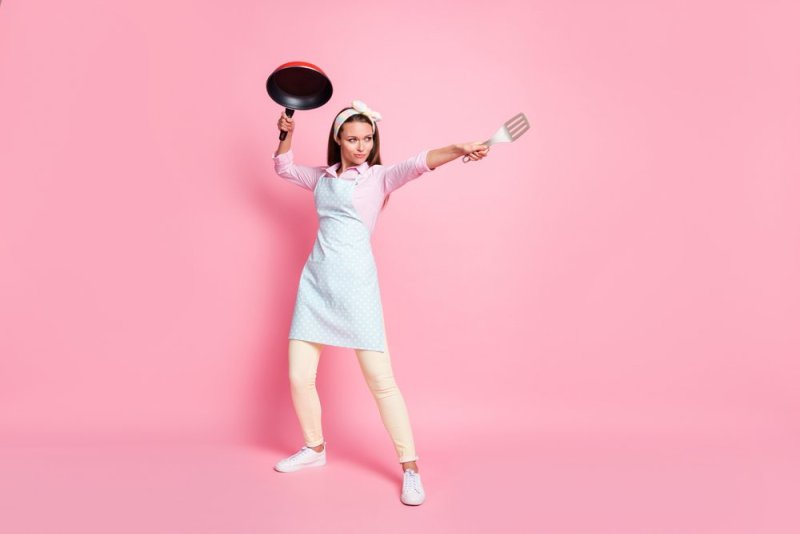 Full-size photo of strong chef woman hold frying pan spatula attack enemies wear shirt pants trousers isolated over pastel color background
