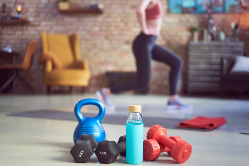 Girl working out at home with weights and water bottle