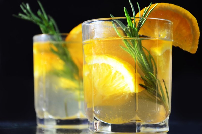 glasses of honey bourbon cocktail with rosemary whiskey sour drink with orange peel, or winter warmer drink punch or mulled wine christmas party cocktail or detox, healthy drink for diet, vitamin c