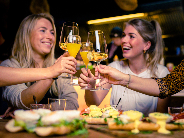 group of women drinking mimosas and wine at brunch