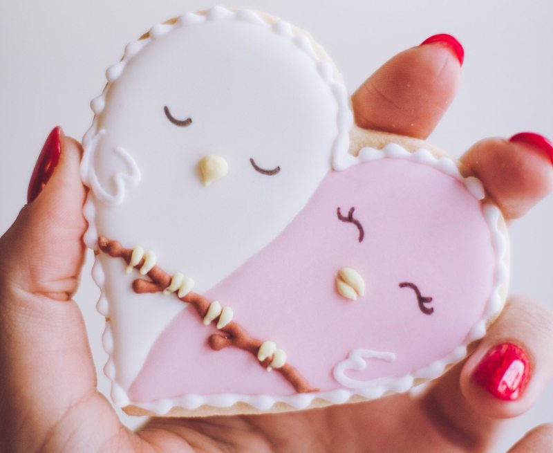 Hand holding pink and white heart cookie