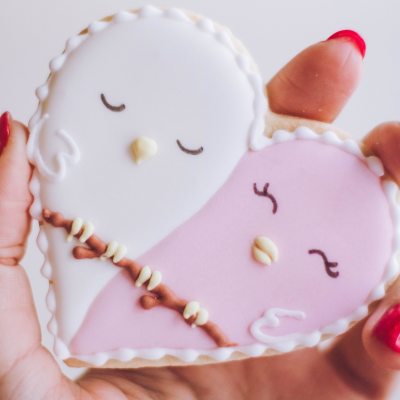 Hand holding pink and white heart cookie