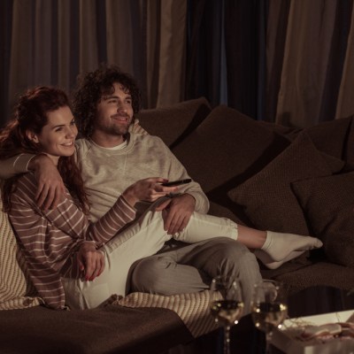 happy couple watching tv on sofa in evening