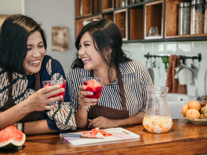 happy mother and daughter making fruit cocktail at home