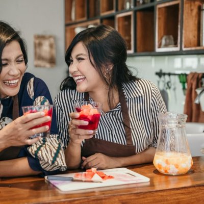 happy mother and daughter making fruit cocktail at home