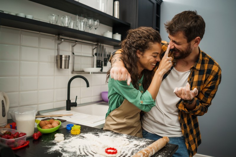 Happy multiethnic couple playfully baking in the kitchen