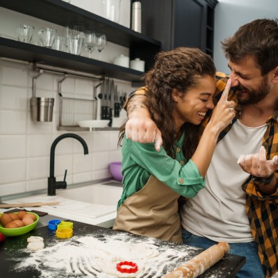 Happy multiethnic couple playfully baking in the kitchen