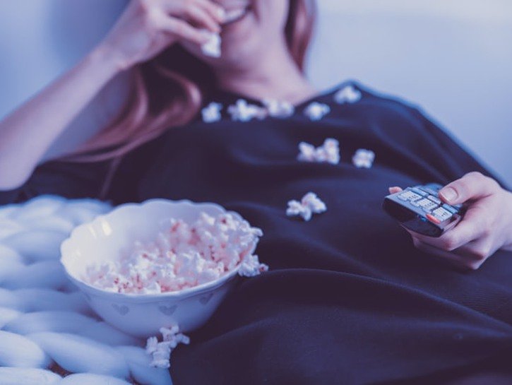 happy woman eating popcorn with remote