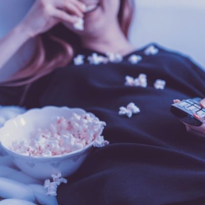 happy woman eating popcorn with remote