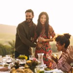 Happy young couple announcing their pregnancy at a party. Man with his girlfriend sharing surprise pregnancy announcement with friends at dinner party.