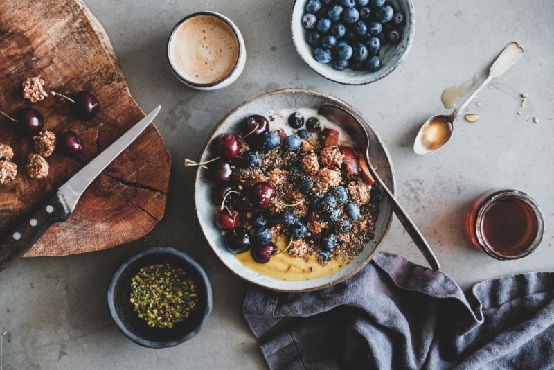 healthy vegan breakfast yogurt bowl with cherries, blueberries, and honey