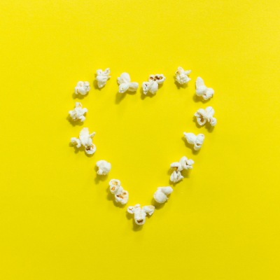 Heart made out of popcorn on yellow background
