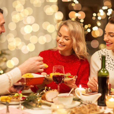 holidays and celebration concept - happy friends having Christmas dinner at home, eating, and drinking