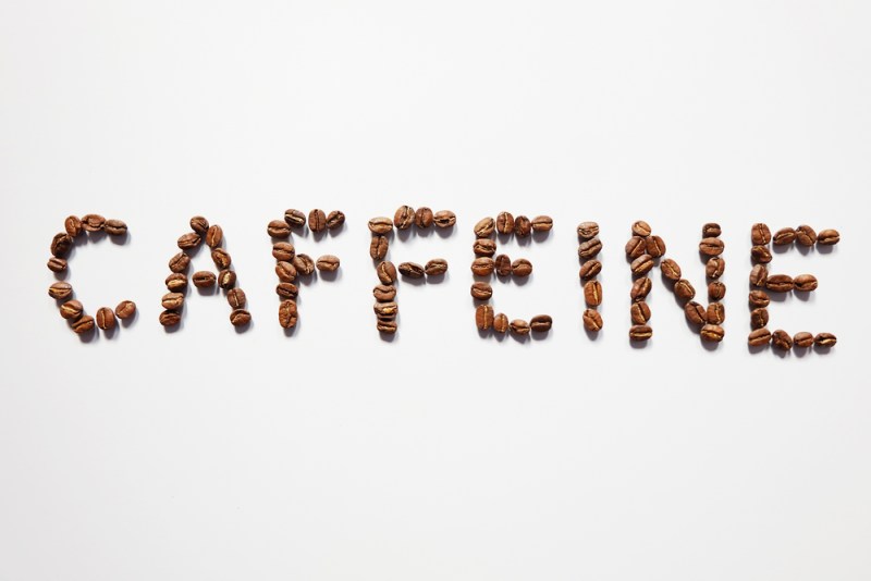 Letter of CAFFEINE arranged with coffee beans on white background