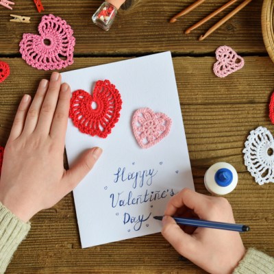 Making of handmade Valentine greeting card with crochet openwork hearts. Making of handmade decoration. Valentines Day crafts. Childrens DIY, hobby concept, gift with your own hands.