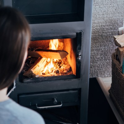 Over the shoulder look of woman tending a wood fired fireplace