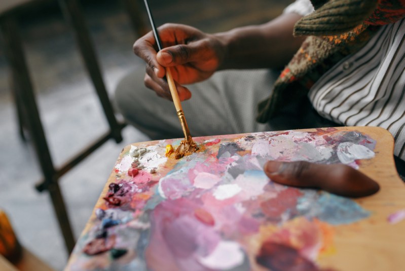 Painter holds brush and colorful paints on palette