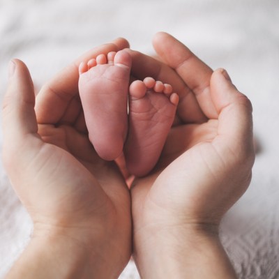 Parent holding in the hands feet of newborn baby.