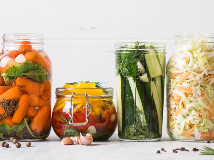 Pickled vegetables. Salting various vegetables in glass jars for long-term storage. Preserves vegetables in glass jars. Variety fermented green vegetables on table