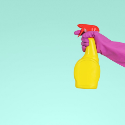 pink gloved hand holding yellow spray bottle