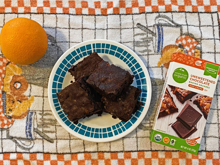 Plate of brownies on towel with baker's chocolate and orange