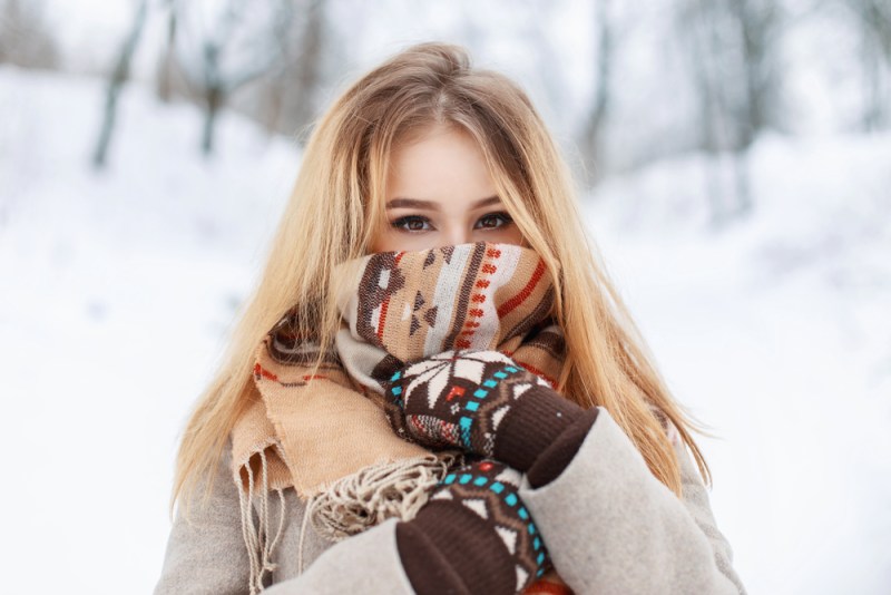 Portrait of a beautiful girl in a scarf and gloves in winter park. Vintage collection. Keep warm