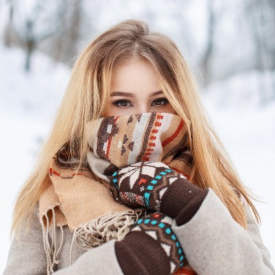 Portrait of a beautiful girl in a scarf and gloves in winter park. Vintage collection. Keep warm