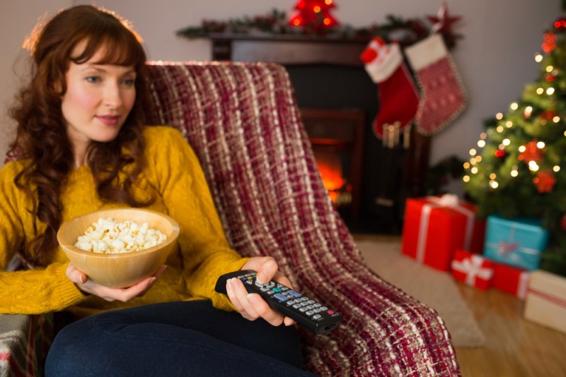 Pretty redhead watching television on couch at christmas at home in the living room