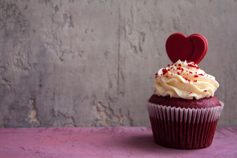 Romantic dessert for a date: red velvet cupcake cream cheese frosting and chocolate heart decorated cupcake. St. Valentine's concept.