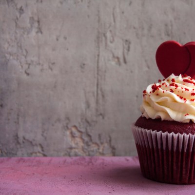 Romantic dessert for a date: red velvet cupcake cream cheese frosting and chocolate heart decorated cupcake. St. Valentine's concept.
