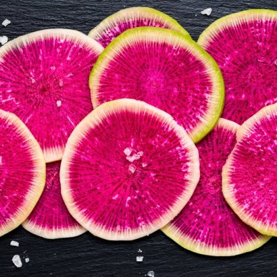 sliced watermelon radish with sea salt on black background. . top view