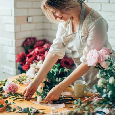 Small business. Male florist unfocused in flower shop. Floral design studio, making decorations and arrangements. Flowers delivery, creating order.
